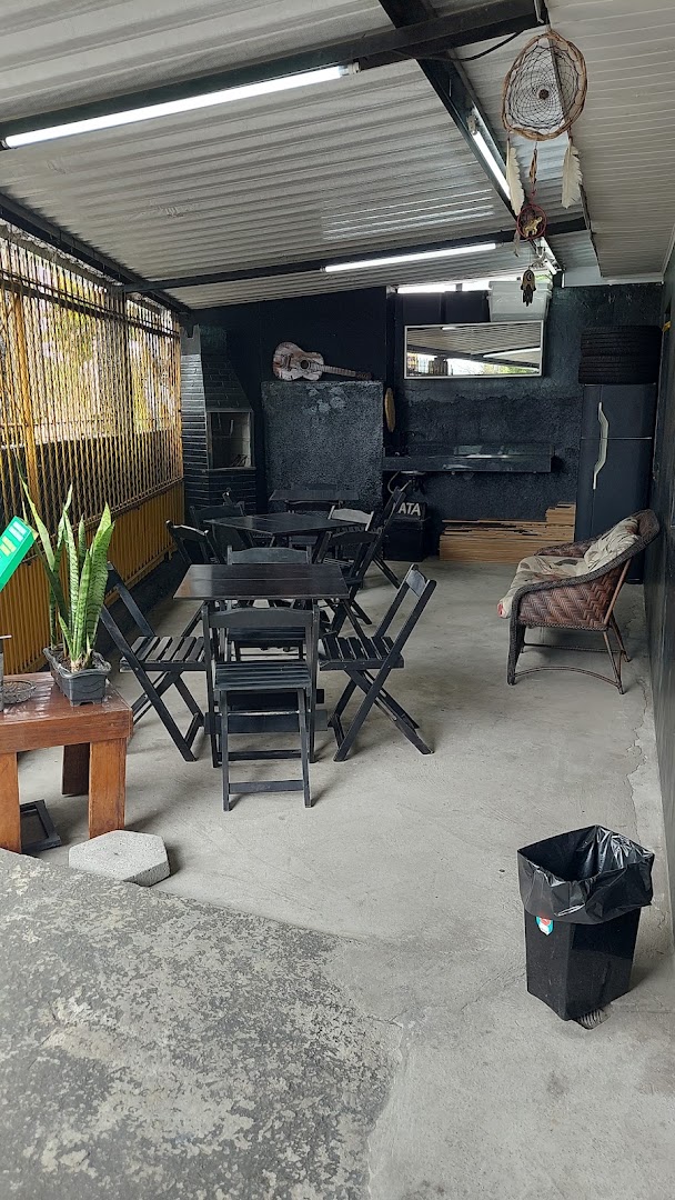 Área de espera coberta da Barbearia Hollywood, com mesas e cadeiras